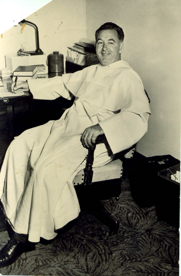 Reverend Cyril Burke, Barry College chaplain, writing at his desk